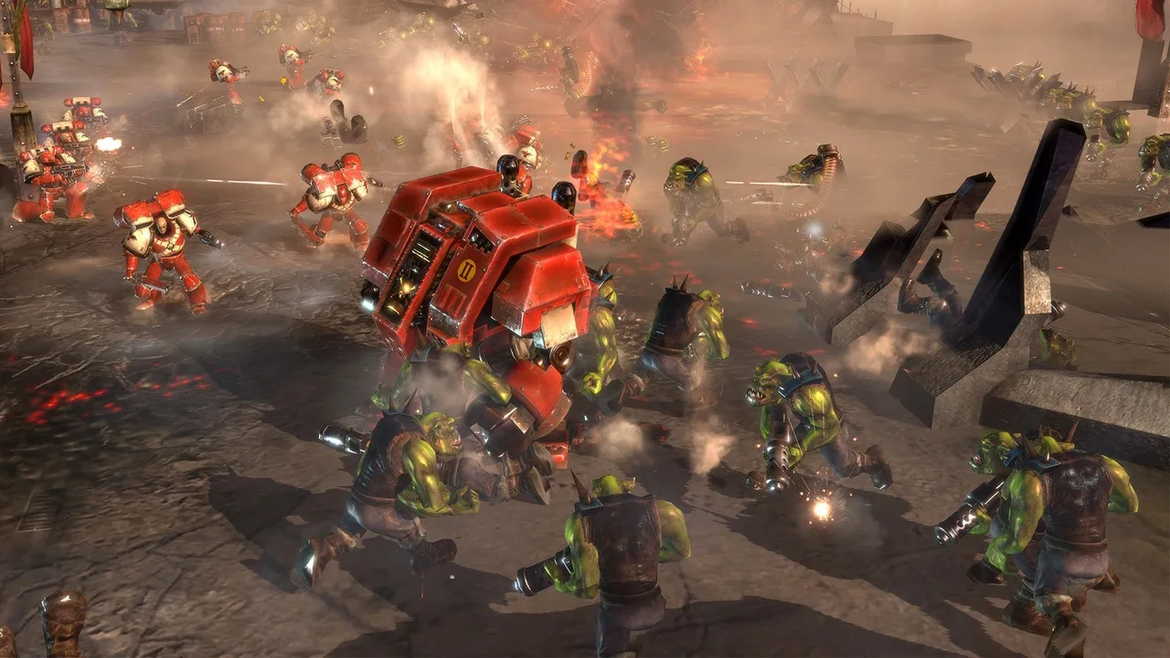 Warhammer 40K csata vörös páncélos űrgárdisták és zöld orkok között egy romos csatatéren.
