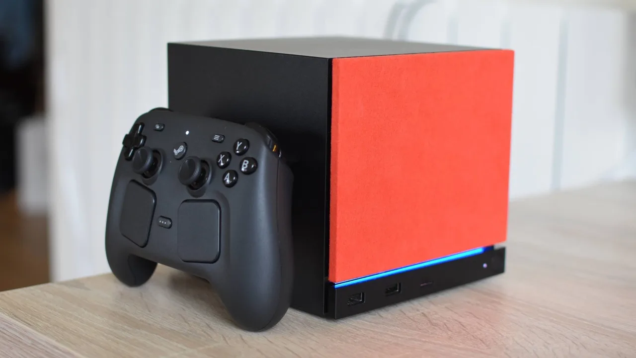 Egy Steam Machine fekete-piros doboz és egy Steam Controller látható egy asztalon.